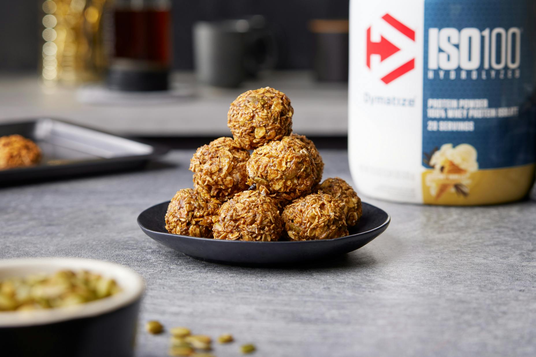 Pumpkin Protein Balls on a counter with a tub of Dymatize nearby