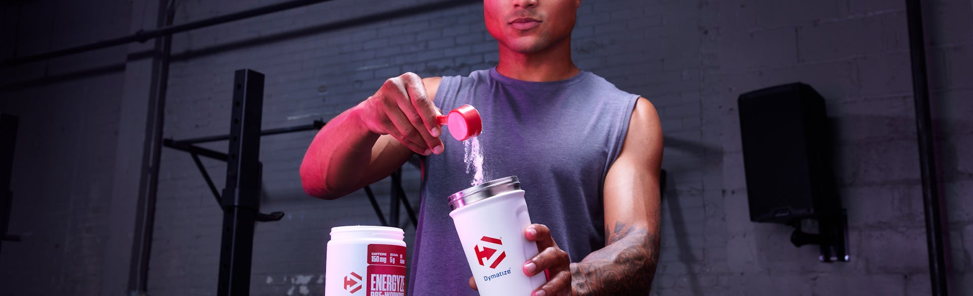 A man scooping Energyze Pre-Workout into a shaker cup.