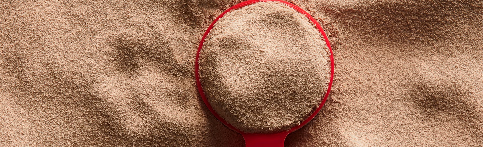 A measuring spoon sitting on top of a mound of Dymatize ISO100 Powder.